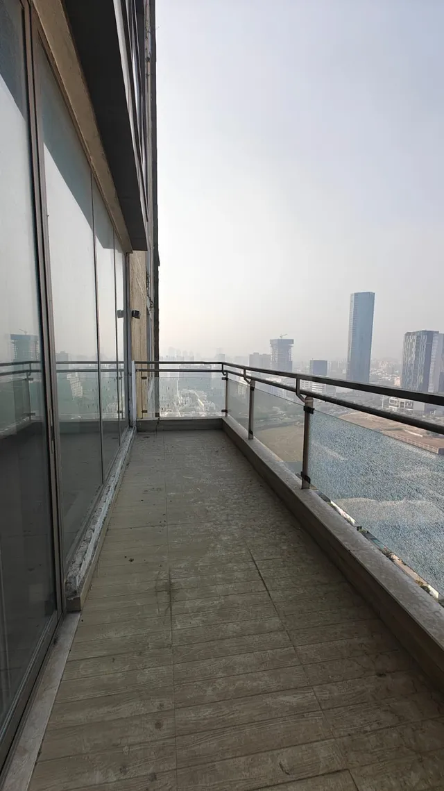 Large wrap-around balcony with glass railings and city skyline views at M3M Golfestate Gurgaon.- The Soni Landbase